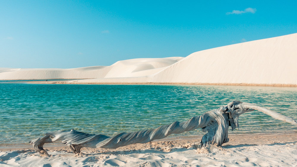 Dunas brancas e lagoa azul em paisagem litorânea